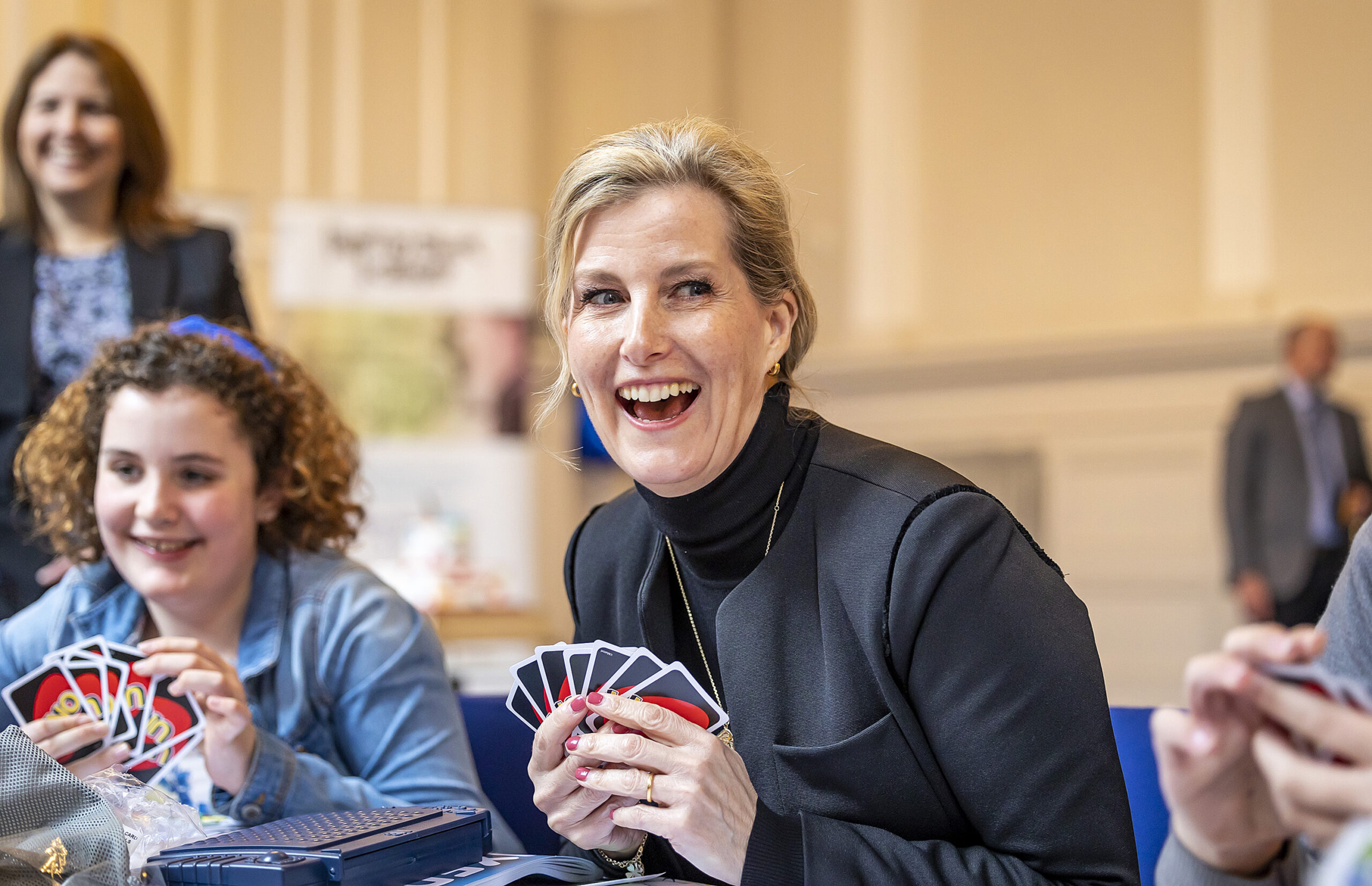 A photograph of HRH The Countess of Wessex laughing while playing uno with some children